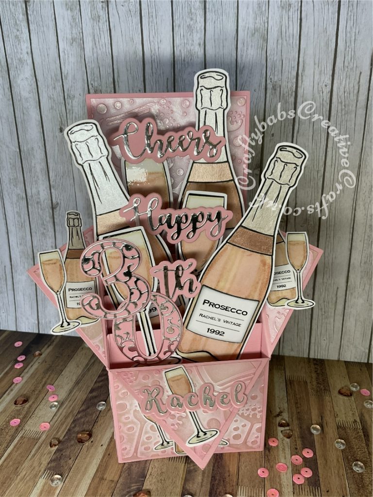 Pink Prosecco themed Pop Up Box card made using various digi-stamps from Craftworld Premium members free digi-stamps cheers collection, dies including; CARD MAKING MAGIC DIE SETS SOLID & OVERLAY NUMBER & SUFFIX, i Craft Cheers & Happy dies, embossing folder and stamps from Issue 161 of Simply cards & Papercraft magazine and Crafters companion Gemini Expressions Metal Die – Uppercase and lower case Alphabet Sets. - craftybabscreativecrafts.co.uk