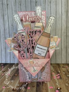 Pink Prosecco themed Pop Up Box card made using various digi-stamps from Craftworld Premium members free digi-stamps cheers collection, dies including; CARD MAKING MAGIC DIE SETS SOLID & OVERLAY NUMBER & SUFFIX, i Craft Cheers & Happy dies, embossing folder and stamps from Issue 161 of Simply cards & Papercraft magazine and Crafters companion Gemini Expressions Metal Die – Uppercase and lower case Alphabet Sets. - craftybabscreativecrafts.co.uk